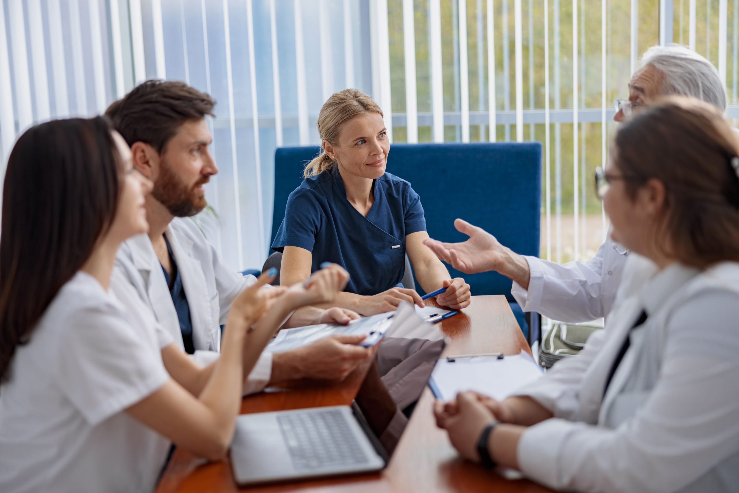 En la imagen se observa a un grupo de profesionales de la salud participando en una reunión de trabajo alrededor de una mesa.